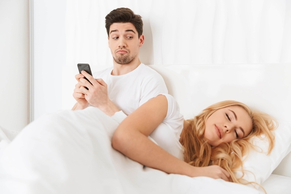 Een man verbergt de telefoon voor zijn vrouw, terwijl hij naar de beste datingsites zoekt